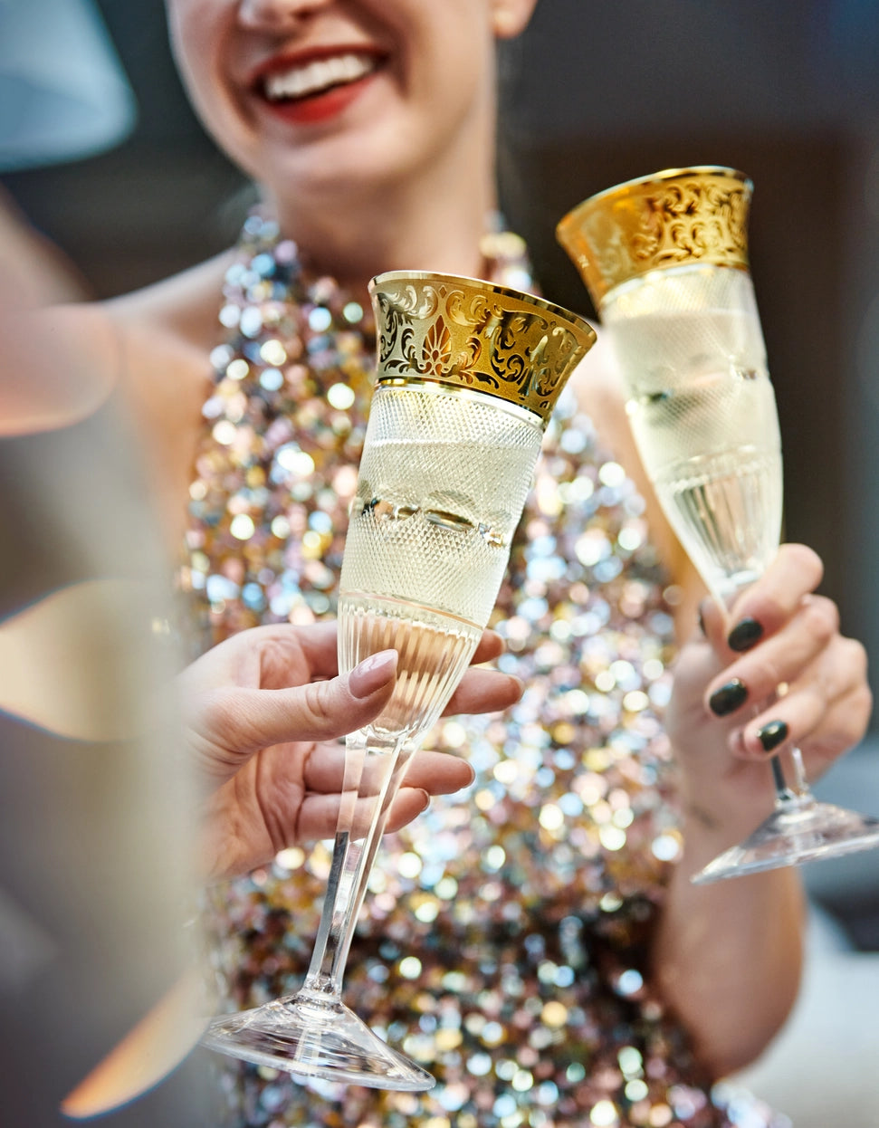 Two women in sequinned dresses each holding Moser's Splendid Champagne Flutes