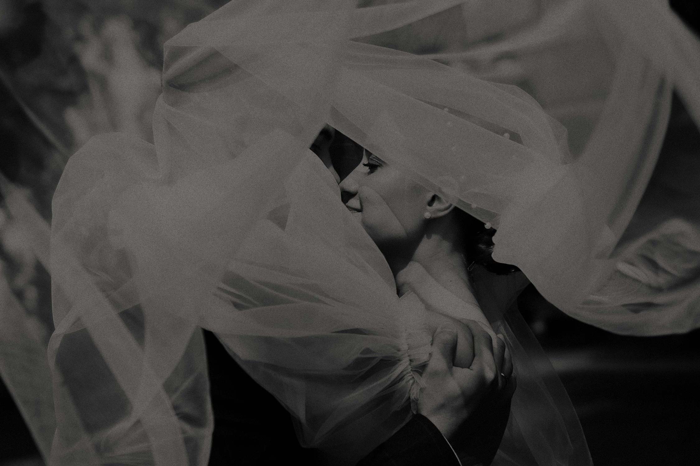 A Bride And Groom Smiling Together Under A Veil